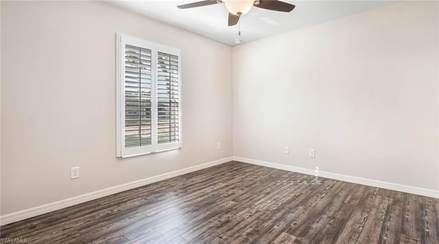 Guest room featuring dark LPV flooring and ceiling fan