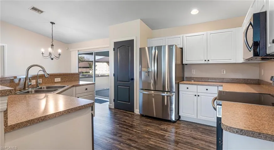 Kitchen with new stainless steel appliances, white cabinets, dark LPV floors, recessed lights