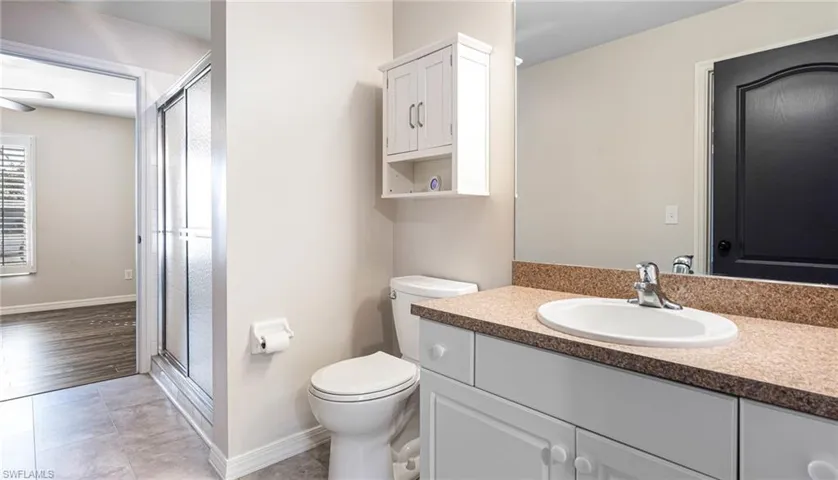 Guest Bathroom with an enclosed shower, toilet, and large vanity