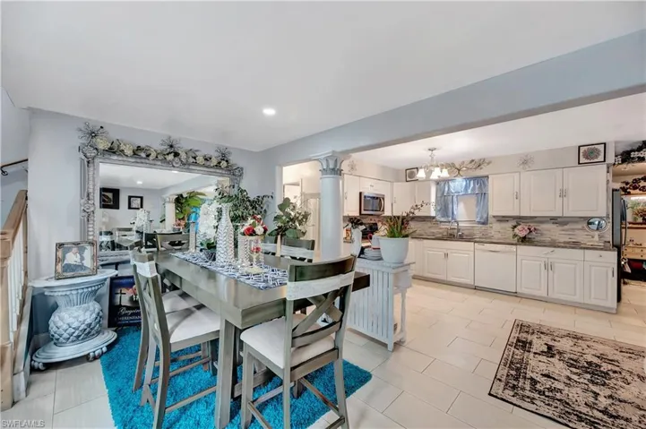 Dining area featuring light tile patterned flooring, a notable chandelier, sink, and ornate columns