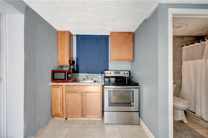 Kitchen with light tile patterned floors, stainless steel appliances, sink, and a textured ceiling