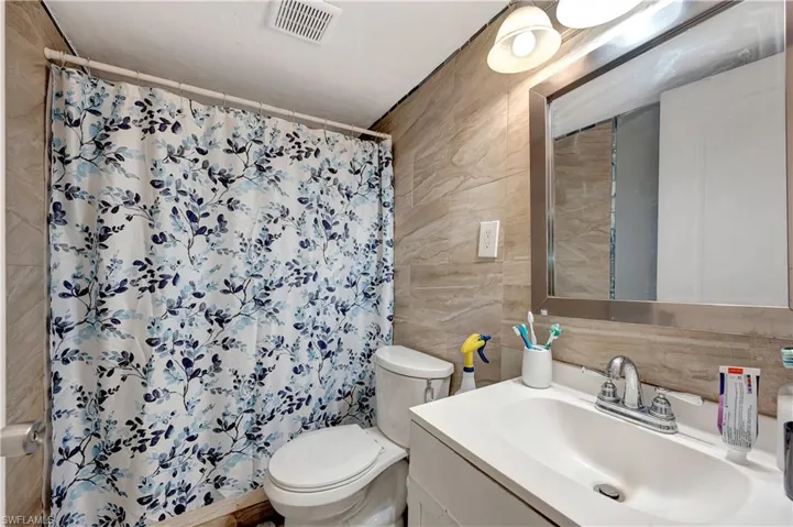Bathroom featuring tile walls, toilet, and vanity