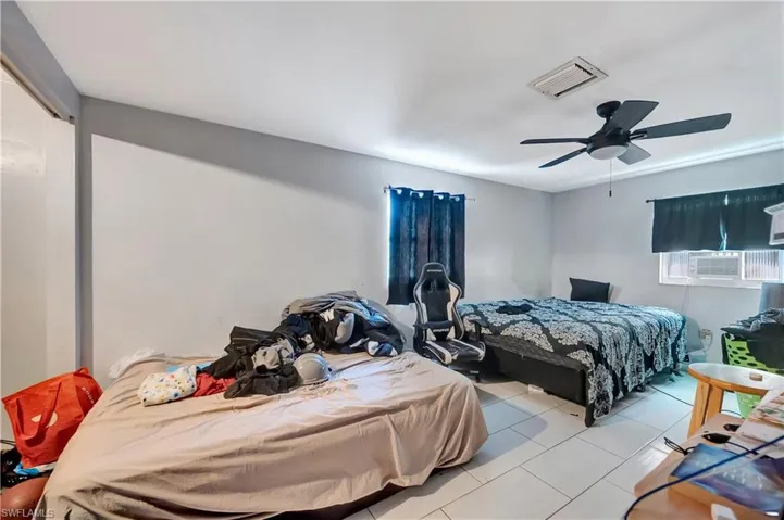 Bedroom with light tile patterned floors, ceiling fan, and cooling unit