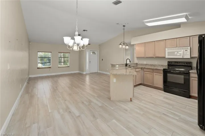 Kitchen with black appliances, lofted ceiling, sink, kitchen peninsula, and light brown cabinets
