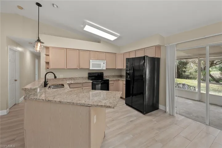 Kitchen with sink, black appliances, kitchen peninsula, and light brown cabinets