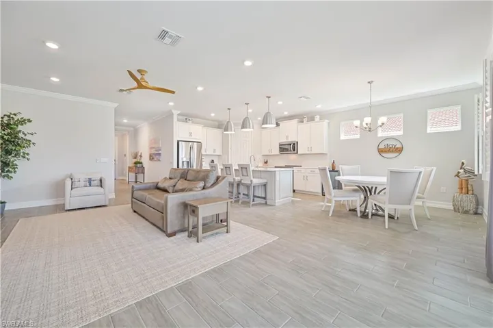 Living area featuring ornamental molding, a chandelier, recessed lighting, baseboards, and light wood-style floors