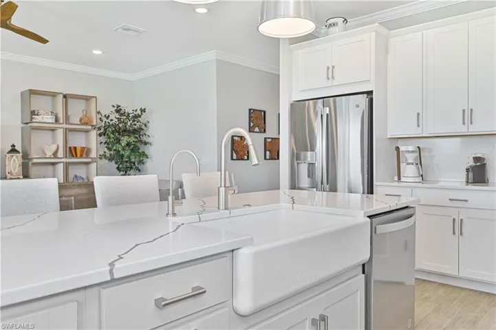 Kitchen featuring appliances with stainless steel finishes, a sink, ornamental molding, white cabinetry, and recessed lighting