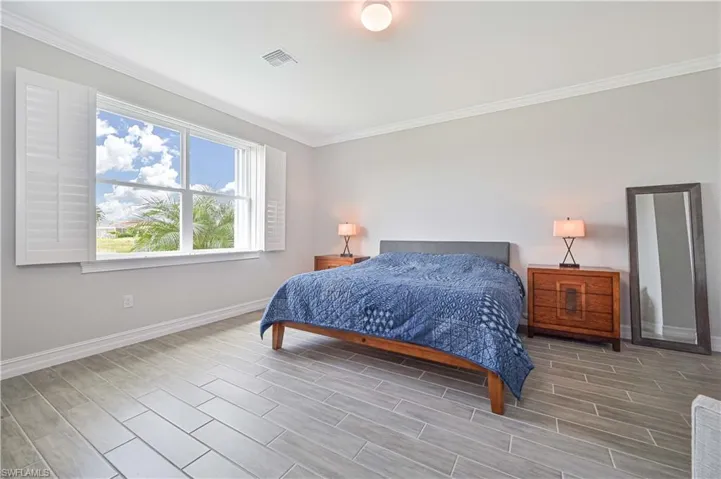 Bedroom with baseboards, ornamental molding, and wood tiled floors