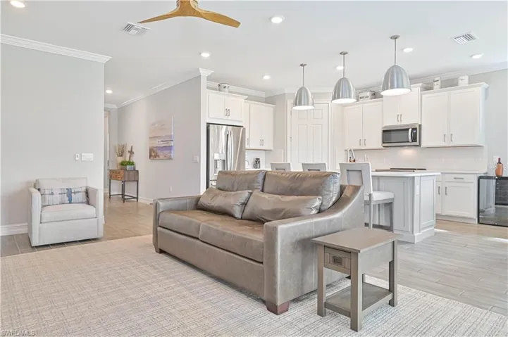 Living area with crown molding, ceiling fan, recessed lighting, wine cooler, and light wood finished floors