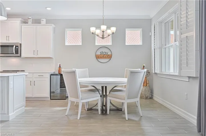 Dining space with a chandelier, crown molding, baseboards, plenty of natural light, and light wood-style flooring