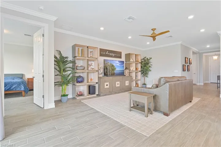 Living room featuring light wood-style flooring, baseboards, ceiling fan, recessed lighting, and crown molding