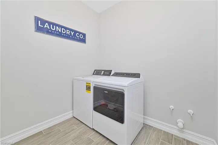 Laundry area featuring wood tiled floors, washing machine and clothes dryer, and baseboards
