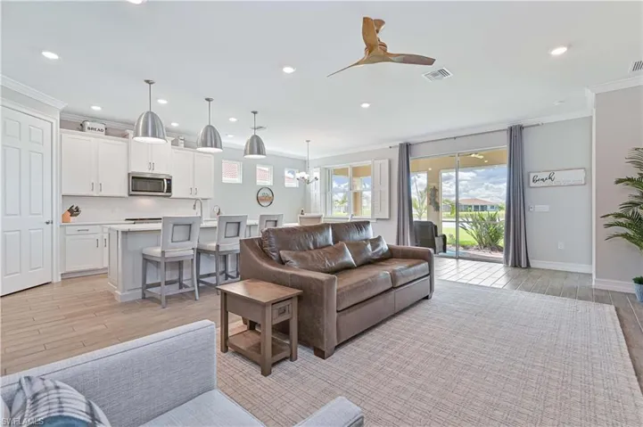 Living room featuring crown molding, recessed lighting, light wood finished floors, a chandelier, and a ceiling fan