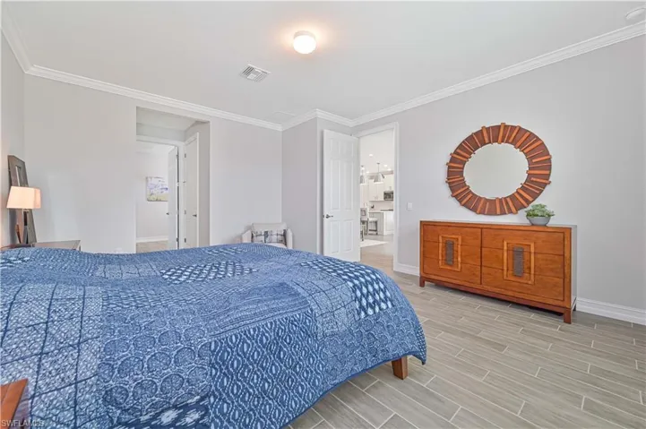 Bedroom with baseboards, wood finished floors, and crown molding