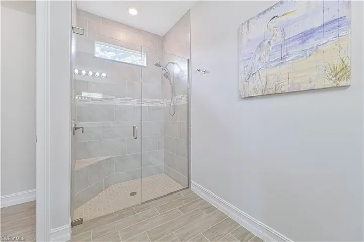 Full bath with baseboards, a shower stall, wood tiled floors, and recessed lighting