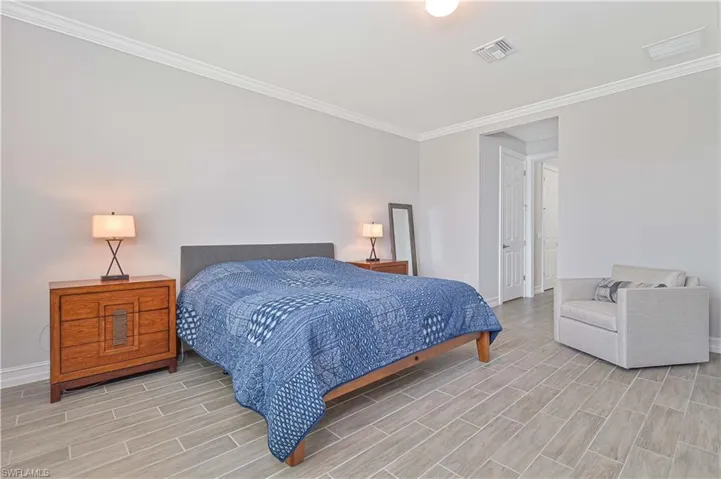 Bedroom with wood finish floors, baseboards, and ornamental molding