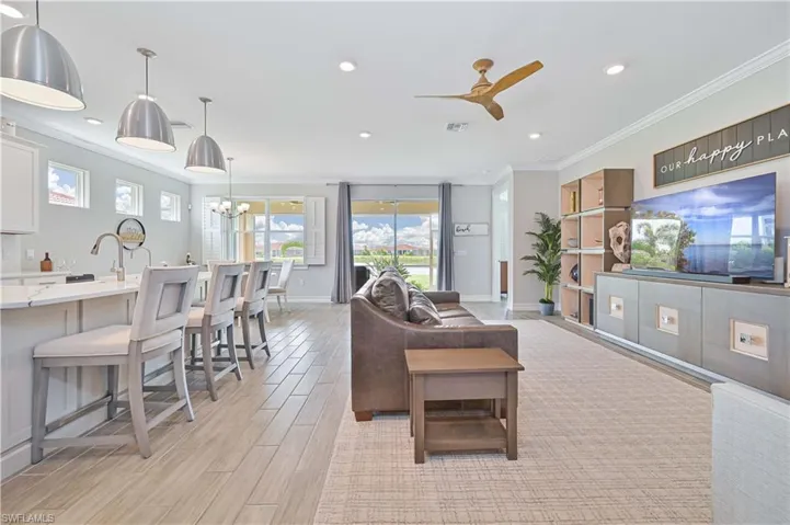 Living room featuring ornamental molding, a ceiling fan, recessed lighting, baseboards, and a chandelier