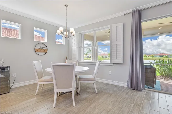 Dining area with ornamental molding, light wood finished floors, a chandelier, and baseboards