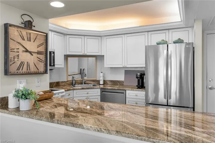 Kitchen with stainless steel appliances, dark stone countertops, and white cabinetry