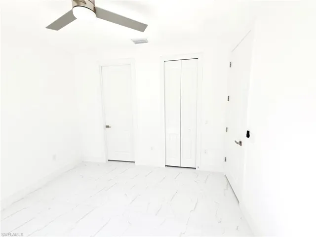 Unfurnished bedroom with a closet, light marble finish floors, and ceiling fan