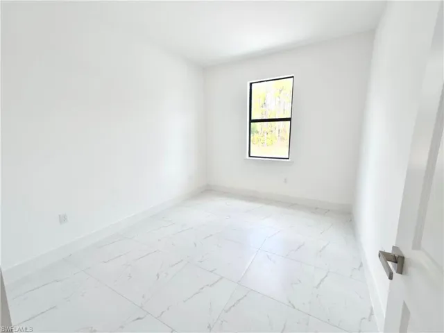 Empty room featuring light marble finish floors and baseboards