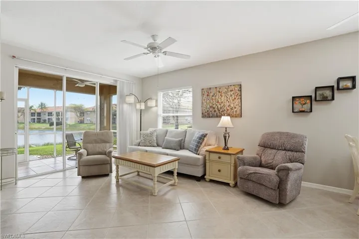 Living area featuring a ceiling fan, a water view, and light tile patterned floors