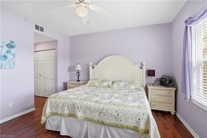 Bedroom with a closet, a ceiling fan, dark wood-style flooring, and multiple windows