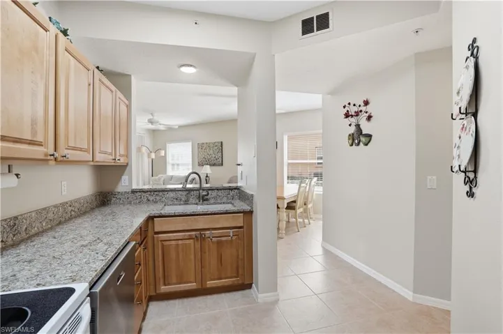 Kitchen featuring electric range, light stone countertops, dishwasher, light tile patterned floors, and a ceiling fan