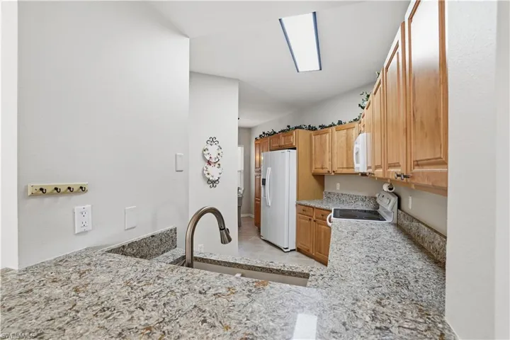 Kitchen with white appliances, light stone countertops, and light tile patterned flooring