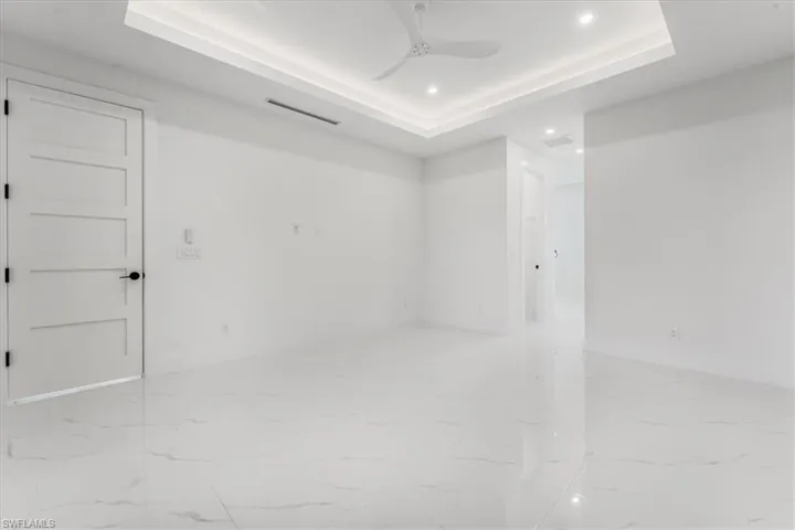 Empty room featuring recessed lighting, a tray ceiling, marble finish floors, and ceiling fan