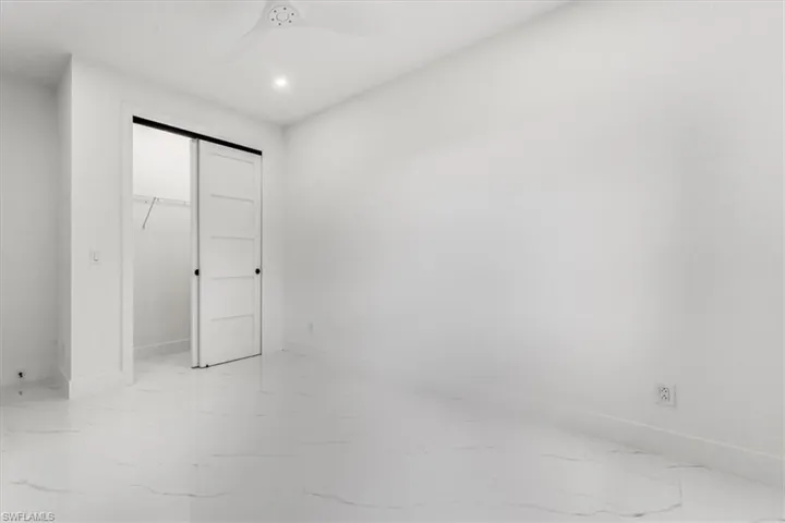 Unfurnished bedroom with a closet, light marble finish floors, and ceiling fan