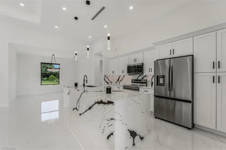 Kitchen featuring appliances with stainless steel finishes, recessed lighting, light marble finish flooring, Calacata Canda Granite, and white cabinetry