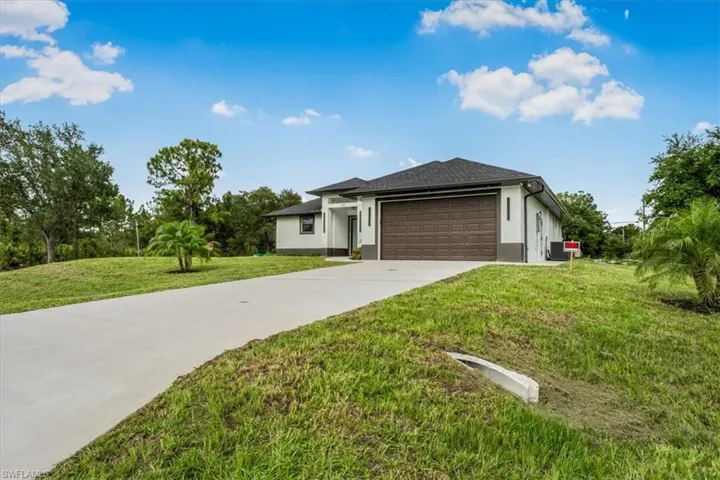 View of front of property featuring stucco siding, an attached garage, concrete driveway, and a front lawn