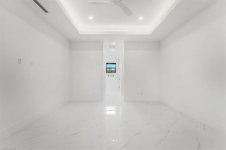 Empty room with recessed lighting, a tray ceiling, marble finish floors, and a ceiling fan