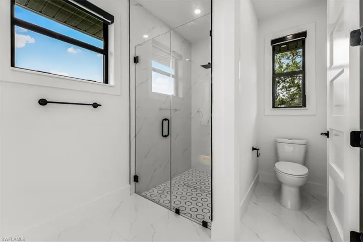 Full bathroom featuring marble look tile flooring, healthy amount of natural light, and a marble finish shower