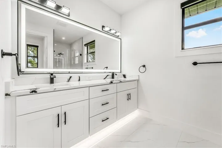Bathroom featuring marble look tiles, a stall shower, and double vanity