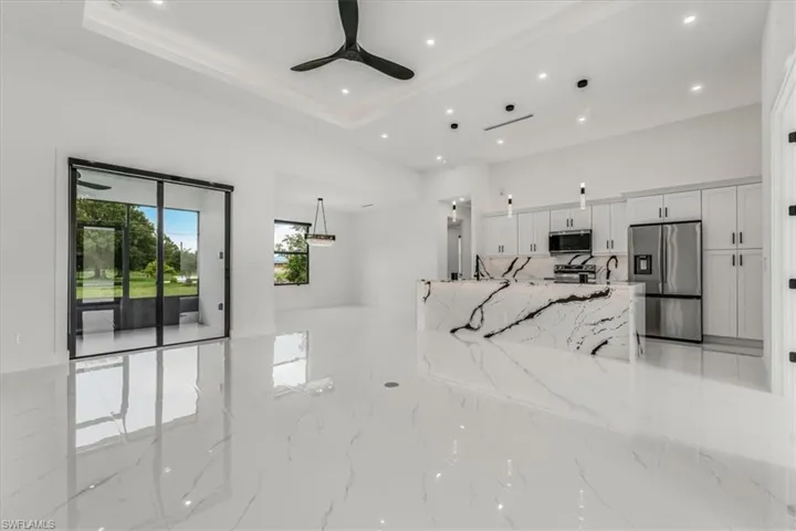 Living room featuring a ceiling fan, recessed lighting, and a tray ceiling