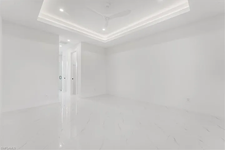 Empty room featuring marble look tiles, recessed lighting, and a raised ceiling
