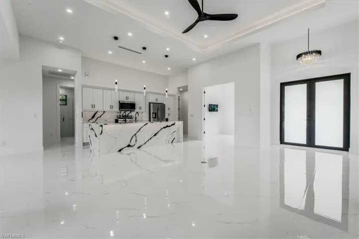 Unfurnished living room featuring recessed lighting, a ceiling fan, and a towering ceiling