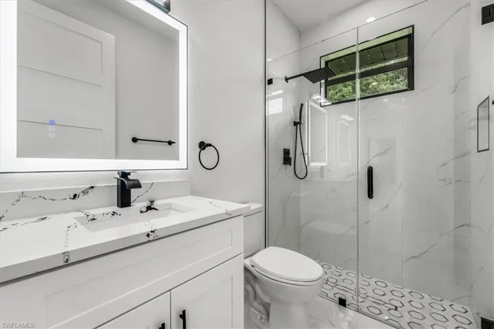 Full bath featuring a marble finish shower and vanity
