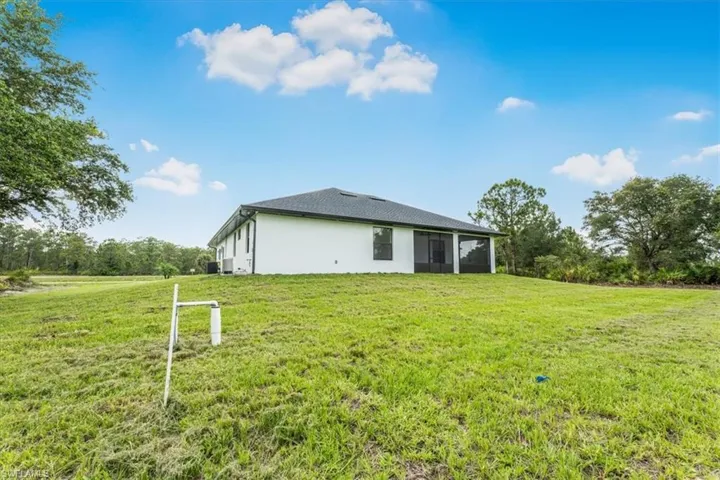 Back of house featuring a sunroom, a lawn, and stucco siding
