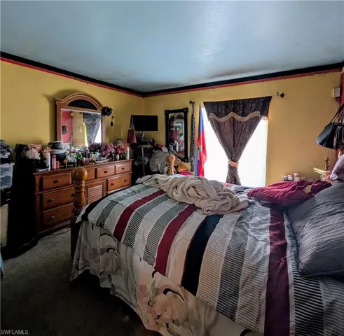 Bedroom featuring multiple windows, dark carpet, and ornamental molding