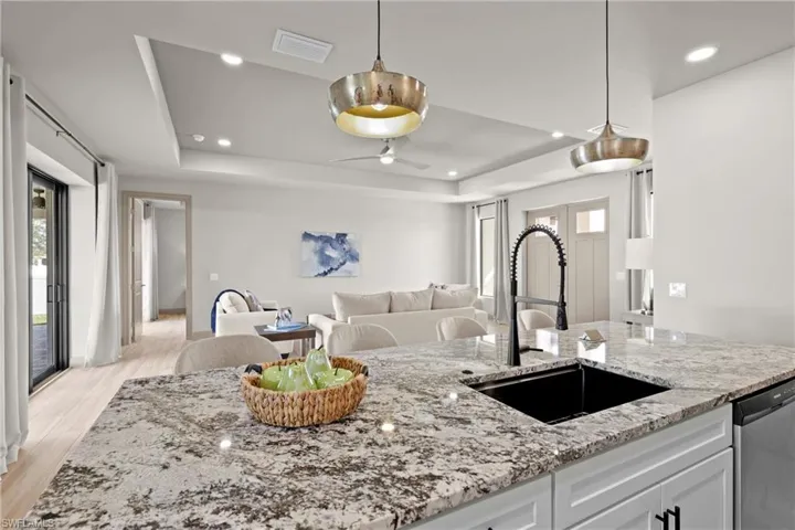 Kitchen featuring light stone counters, stainless steel dishwasher, sink, white cabinets, and light hardwood / wood-style floors