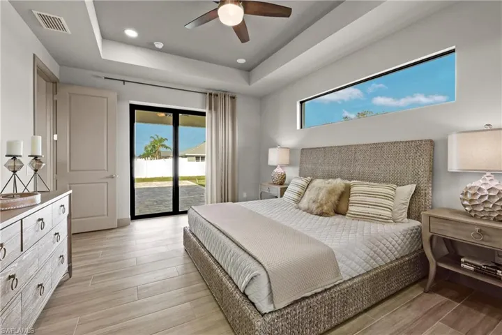 Bedroom with a raised ceiling, ceiling fan, access to exterior, and light hardwood / wood-style flooring
