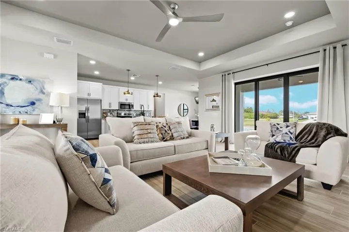 Living room featuring light hardwood / wood-style floors, ceiling fan, and a tray ceiling