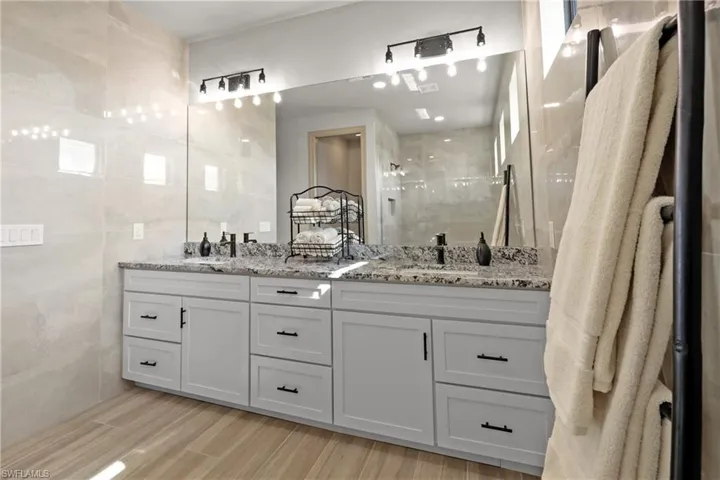 Bathroom featuring a shower, hardwood / wood-style floors, vanity, and tile walls
