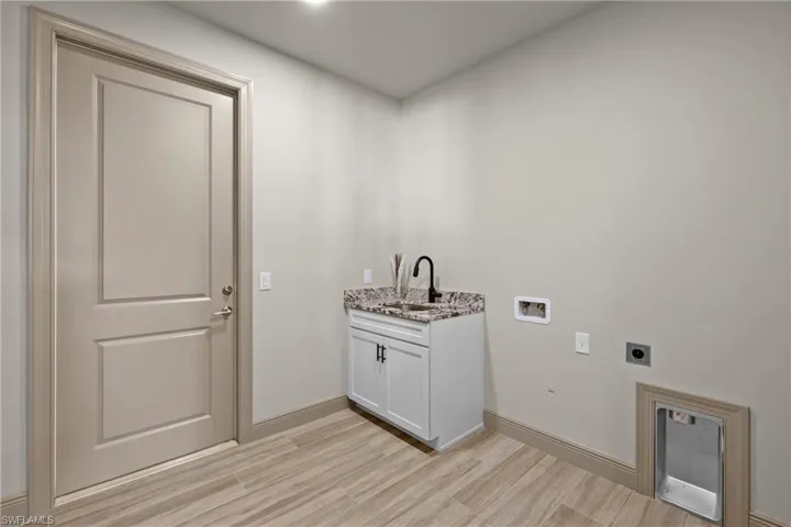 Laundry room featuring sink, cabinets, electric dryer hookup, hookup for a washing machine, and light hardwood / wood-style floors