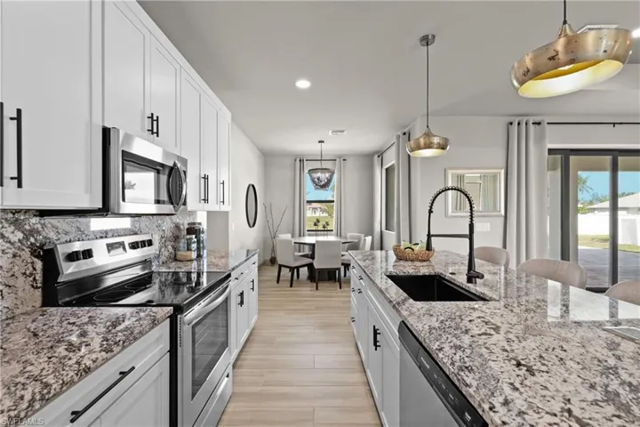 Kitchen featuring white cabinets, sink, stainless steel appliances, and a wealth of natural light