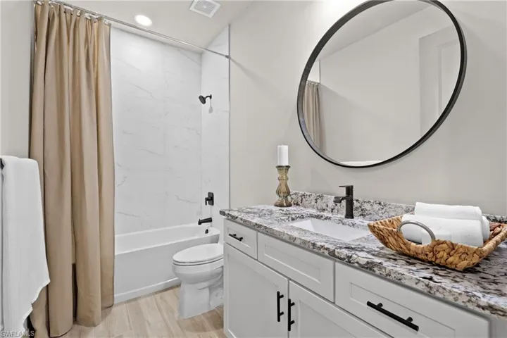 Full bathroom with toilet, vanity, hardwood / wood-style flooring, and shower / tub combo with curtain