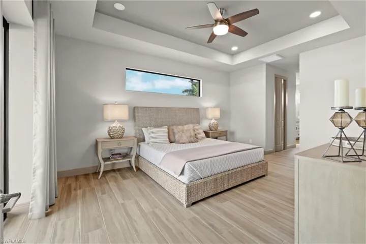 Bedroom with ceiling fan, light hardwood / wood-style floors, and a raised ceiling